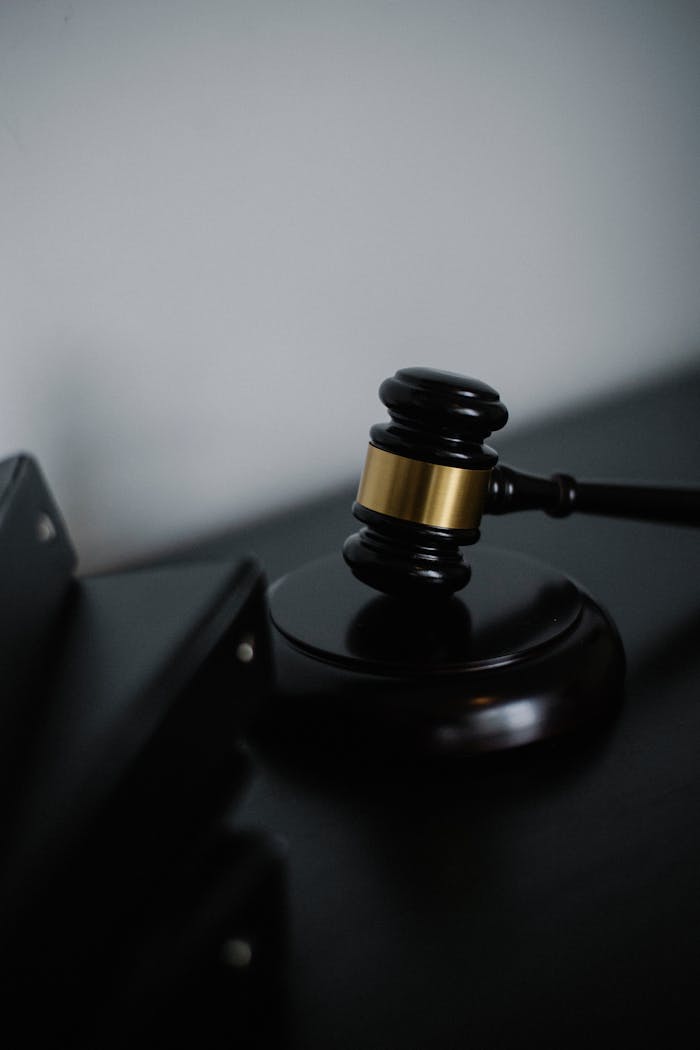 our-story Black wooden gavel with golden strip on table near stack of folders in courthouse