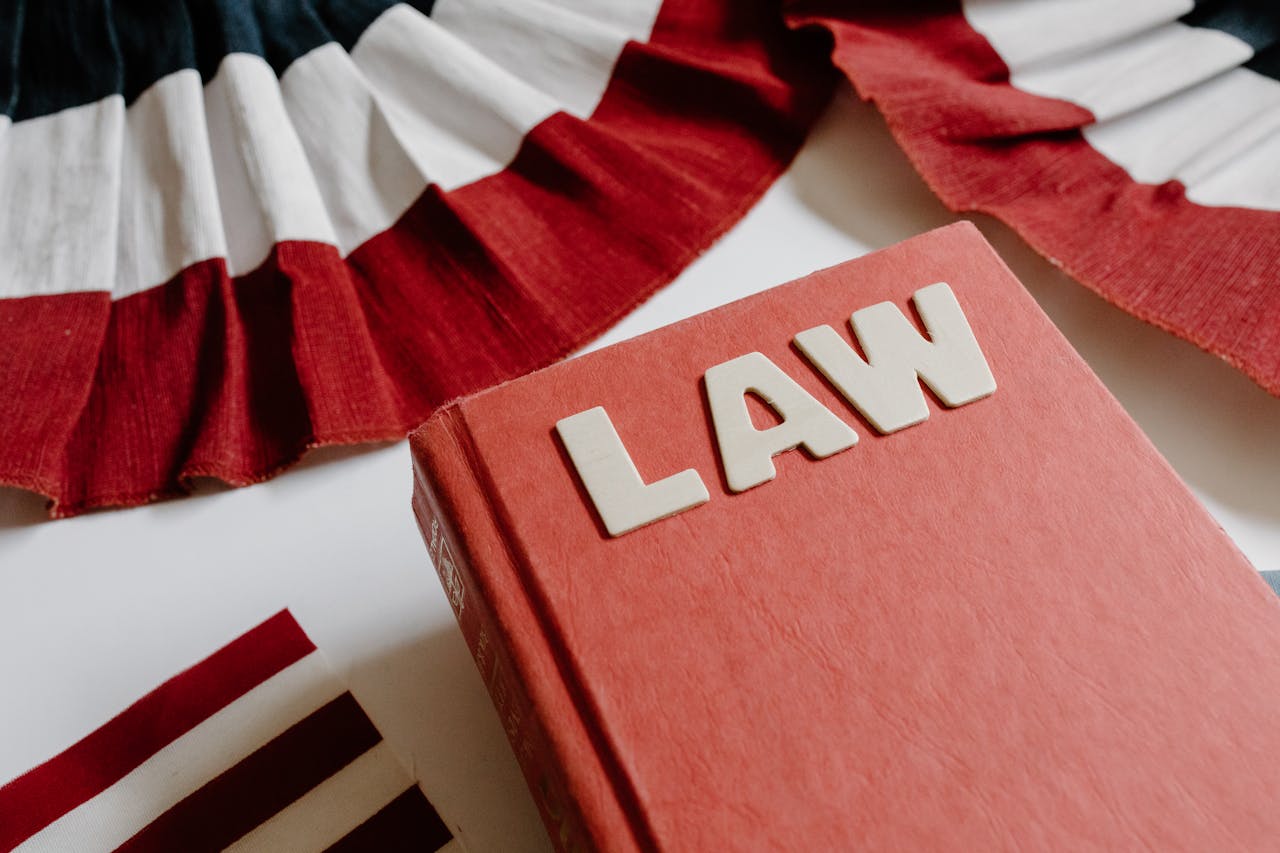 A law book with bold letters placed beside a red, white, and black decorative ribbon.
